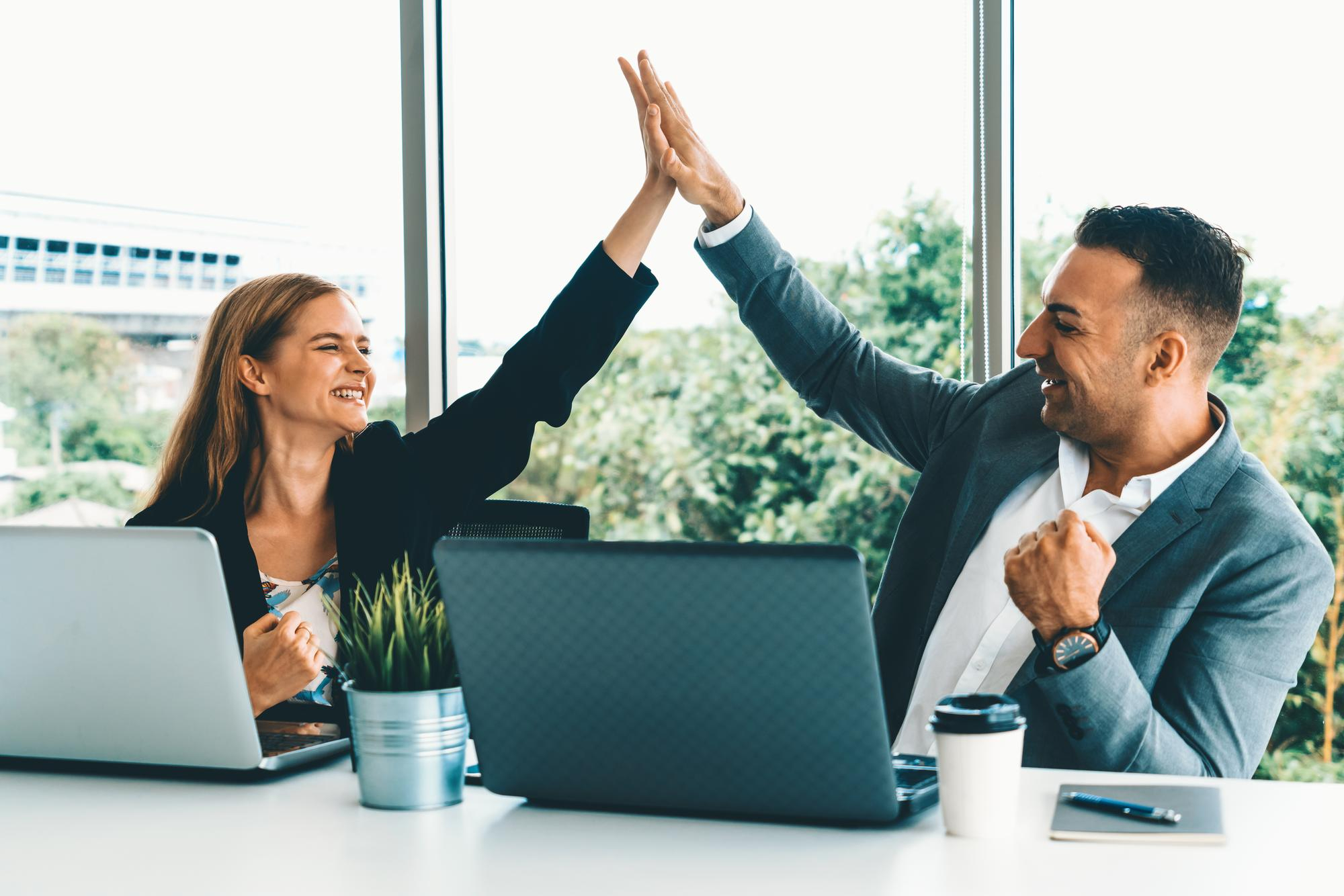 Two people giving a hi-fi in a office environment.